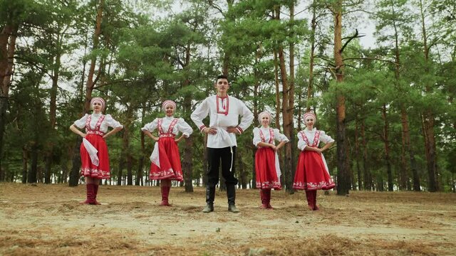 One man and four young women are dancing Russian Traditional dances in summer forest