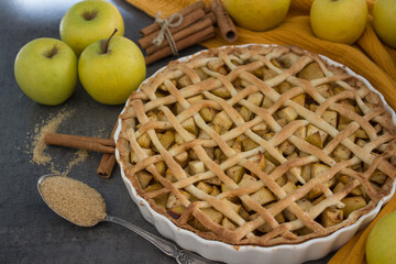 Lattice decorated apple pie on a table. Top view photo of apple tart on yellow fabric background.  Homemade dessert pie close up. 