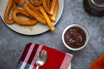 creamy hot chocolate and churros on a concrete table. Top view
