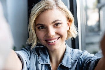 blonde woman smiling and looking at camera with blurred foreground