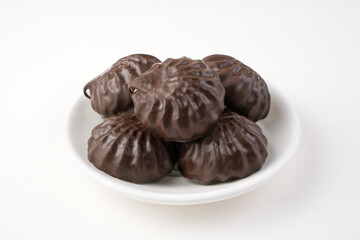 Chocolate-covered marshmallows on a white plate. Side view. The concept of acertou.