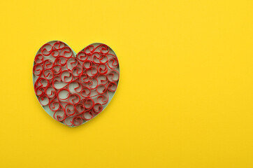 A red origami heart on yellow background