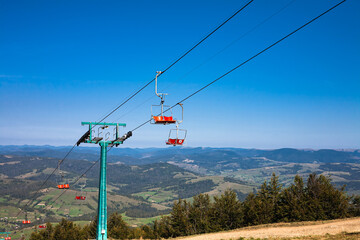 Empty mountain ski chairlift in summer. Forest mountains panorama on the horizon. Travel concept.
