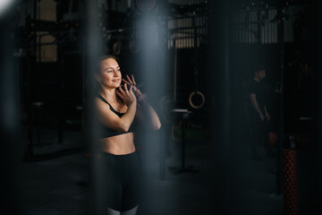 Fototapeta na wymiar Muscular young woman with perfect athletic body wearing black sportswear working out with kettlebell during sport workout training at modern fitness gym with dark interior.