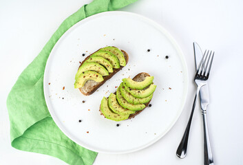 Culinary background with avocado sandwiches on a white background with Cutlery and napkin. The view from the top. Concept of healthy dishes.