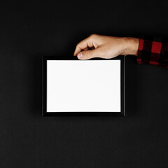 Photo frame in hands on a black background. Preparation for text, mockup, copy space.