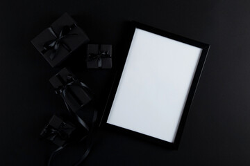 Black gift and mockup frame, on paper black background. Dark design concept, sales. Copy space.