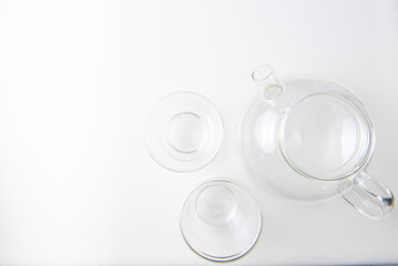 set of glassware transparent teapot and two mugs on white background