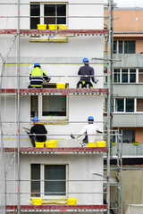 builders apply decorative plaster to the facade of the apartment house to be renovated