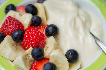 Yogurt with fresh strawberries, blueberries and banana. Closeup homemade healthy morning breakfast with selective focus.