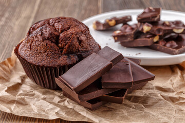 Chocolate cupcake with icing and chocolate bar in Dark lighting,Homemade delicious chocolate muffin on wooden background close-up