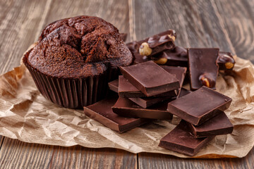 Chocolate cupcake with icing and chocolate bar in Dark lighting,Homemade delicious chocolate muffin on wooden background close-up