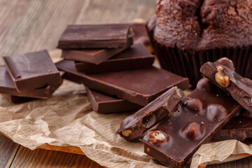 Chocolate cupcake with icing and chocolate bar in Dark lighting,Homemade delicious chocolate muffin on wooden background close-up