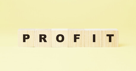 word profit made with wooden cubes on yellow background