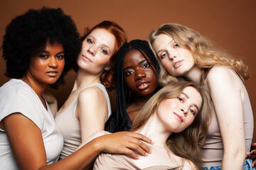 Obraz premium young pretty african and caucasian women posing cheerful together on brown background, lifestyle diverse nationality people concept