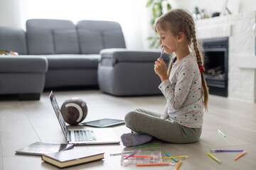 portrait of little sportive girl with rugby ball looking at laptop