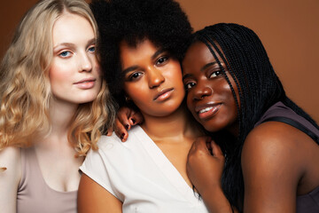 Obraz premium young pretty african and caucasian women posing cheerful together on brown background, lifestyle diverse nationality people concept
