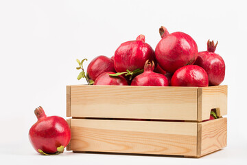 Pomegranate fruits in wooden box on white background