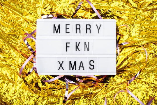 Light boxing with the words merry fkn xmas on a golden background. New Year's Eve and content.