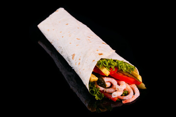 Delicious turkish doner kebab with shrimps, tomatoes, lettuce, parsley, cucumbers and sauce isolated on black background	