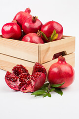 Pomegranate fruits in wooden box on white background
