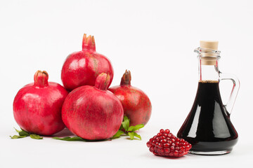 Grenadine in bottle and pomegranates on white background