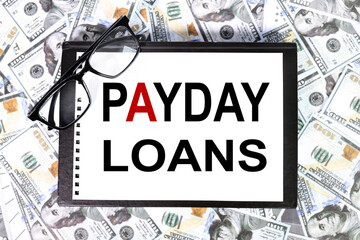 PAYDAY LOANS, text on white paper ON the background of money, banknotes, dollars