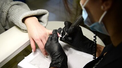 the manicurist removes the old gel polish from the client's nails. polish remover sander. machine for manicure.