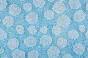 White round plastic foam sheet pieces on blue background. Winter snowfall concept. Torn foam...