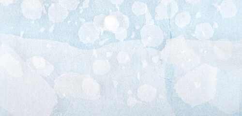 White round plastic foam sheet pieces on blue background. Winter snowfall concept. Torn foam polyethylene transparent pieces as snowflakes.