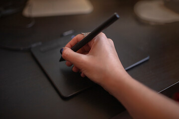 designer girl's hands draw on a graphics tablet at home studio