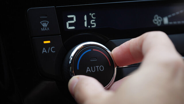 set up air conditioner in the car. Hand turns air conditioner ring. Display indicates temperature inside the car.