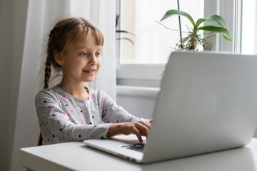 Little girl studying online using her laptop at home