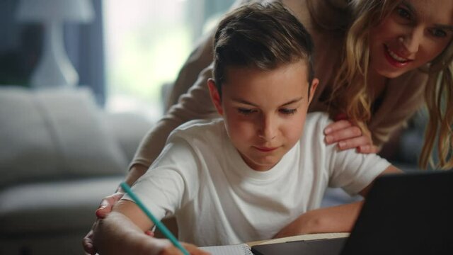 Mom helping son doing homework. Mother cheering up kid during distance education