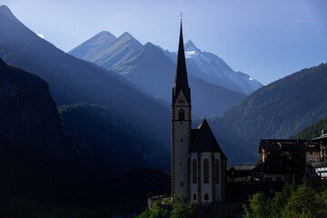 Fototapeta premium The parish church in Heiligenblut with the Grossglockner in the background in late evening sun