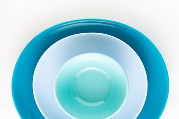 Shades of blue and teal colored elliptical shaped plates and bowls on white background