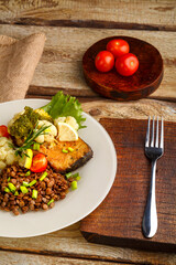 Baked fish with broccoli and lentils in a plate with rosemary and lemon.