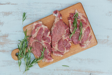 Raw fresh meat steak entrecote, rosemary and seasonings on a cutting board.