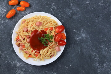 Italian spaghetti pasta with cherry tomatoes, tomato sauce, basil, fried carrots and sausage on a dark table, top view, place for text, selective focus