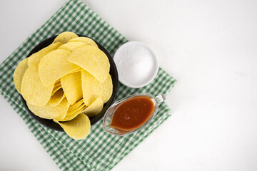 Chips in a wooden bowl with barbeque sauce and salt
