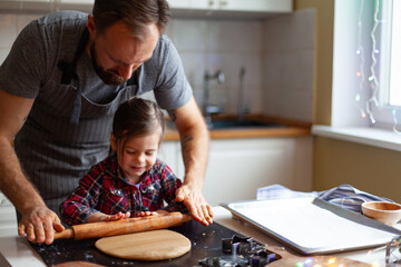 Hands of Father and daughter making cookies with tins on prepared dough. New year Christmas concept