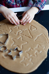 Preparation of ginger biscuits. A woman cuts out cookies as a star shape. Pastry cooking, homemade cuisine concept.