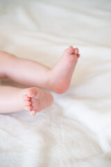 Obraz na płótnie Canvas tiny, cute, bare feet of a little caucasian baby girl or boy on a white soft and cosy background, with pink skin, playfully wriggling its toes in excitement 