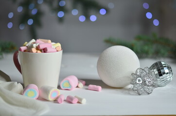 Marshmallows and Christmas balls on bokeh background.