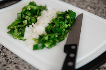 Bell pepper and onion cut with a knife to prepare a meal