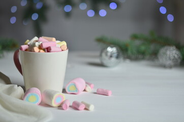 Cup full of marshmallows. Christmas balls are blurred.