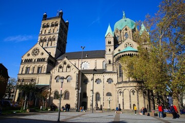 Fototapeta na wymiar Neuss, Germany - November 7. 2020: View over square on on roman catholic Quirinus church basilica with trees in autumn colors