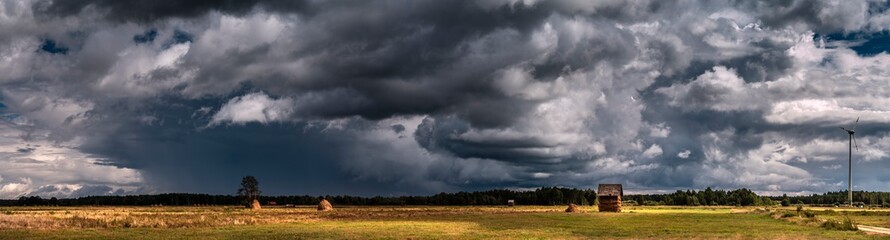Fototapeta na wymiar Dramatic view of a shelf cloud over a field, horizontal cloud formation, panorama view.