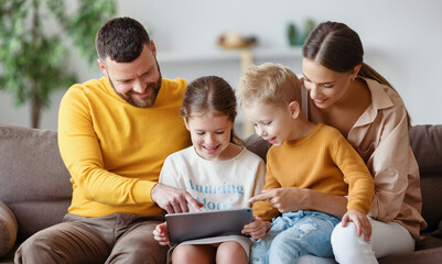 Smiling family using tablet together on sofa.