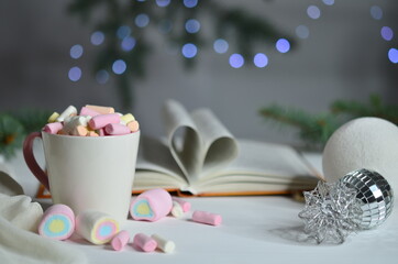 Marshmallow, book and Christmas balls on bokeh background.
